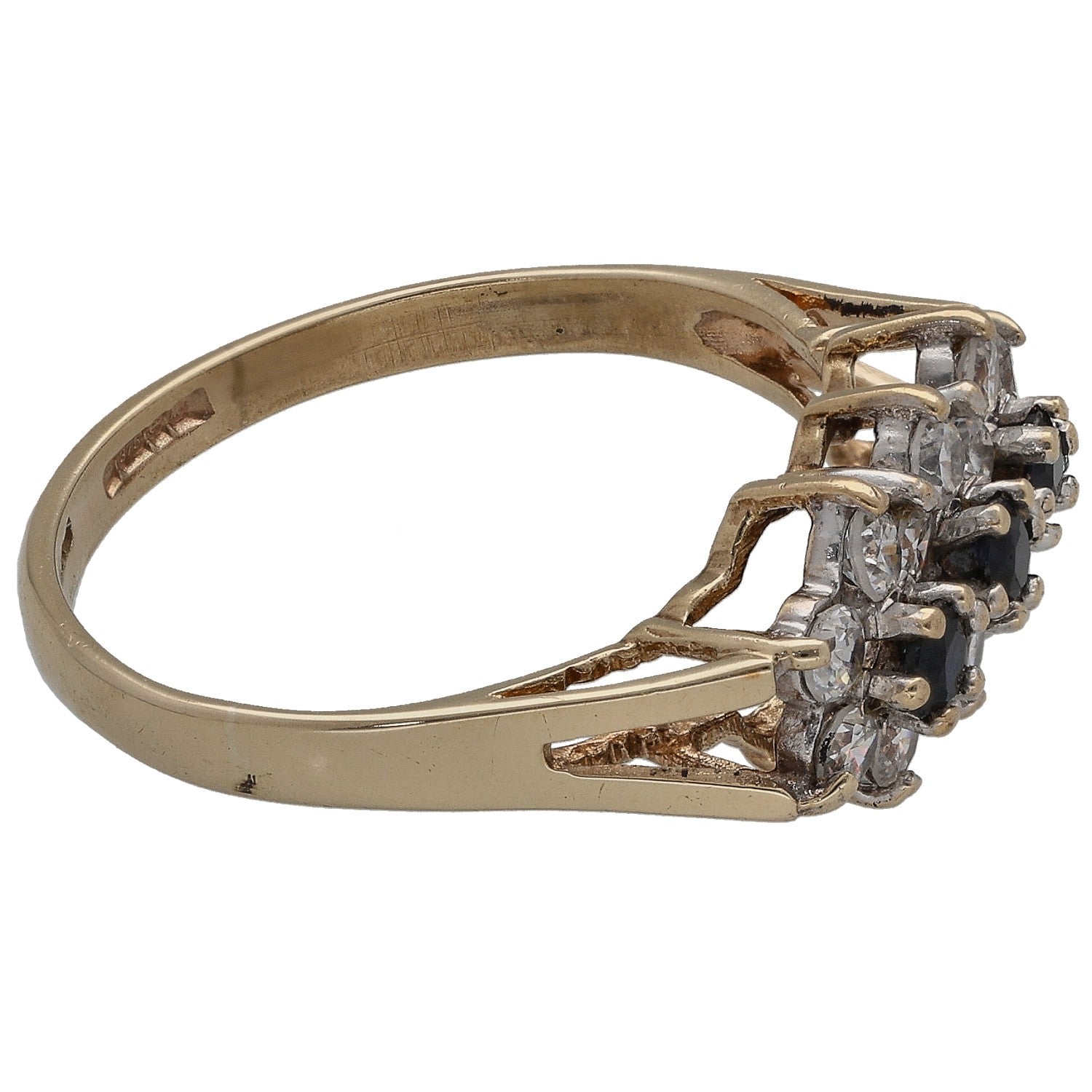 Gold cocktail ring with raised cluster of dark blue and clear stones, side view