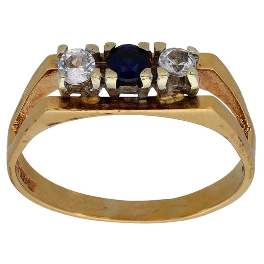 Gold-tone three-stone ring with two clear stones and a dark blue center stone