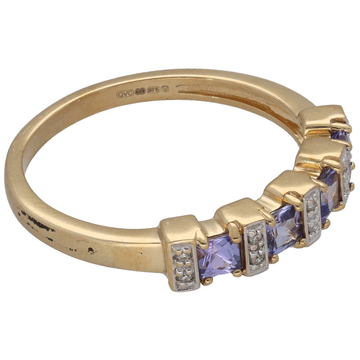 Gold ring side view with purple gemstone set in prongs and baguette diamond accents
