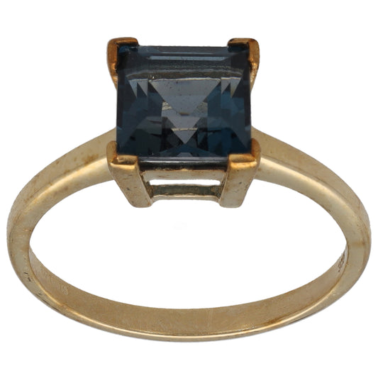 Gold ring with square dark blue gemstone in four-prong setting