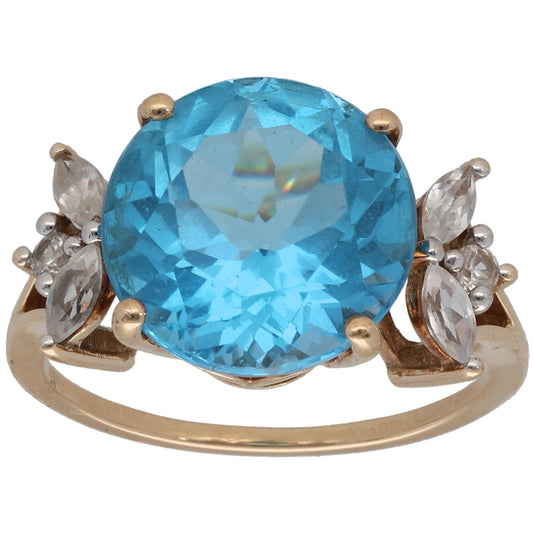 Gold cocktail ring with large blue gemstone and clear side stones