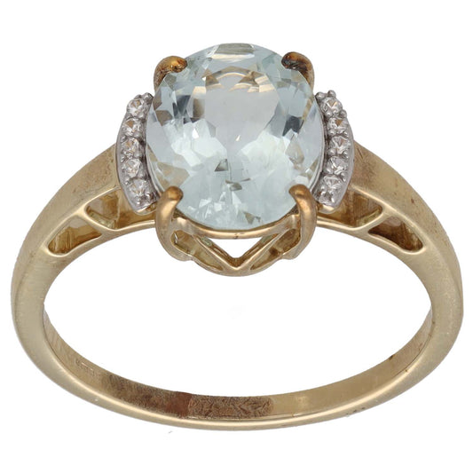 Gold cocktail ring with oval pale blue stone and small clear side stones