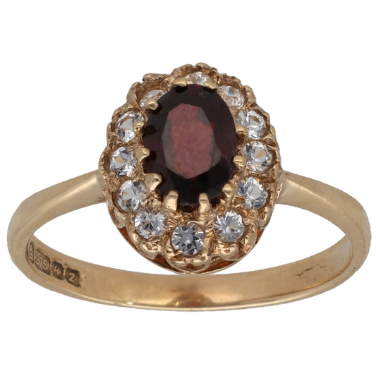 Gold-tone cocktail ring with oval dark red gem and clear stone halo