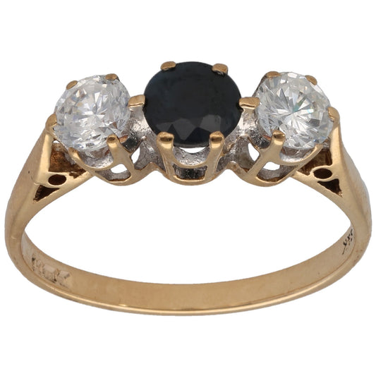 Gold three-stone ring with a dark center gemstone and two clear round stones on prongs