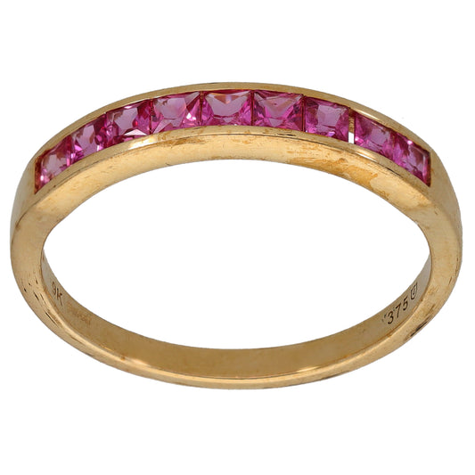 Gold half eternity ring with pink gemstones across the top of the band
