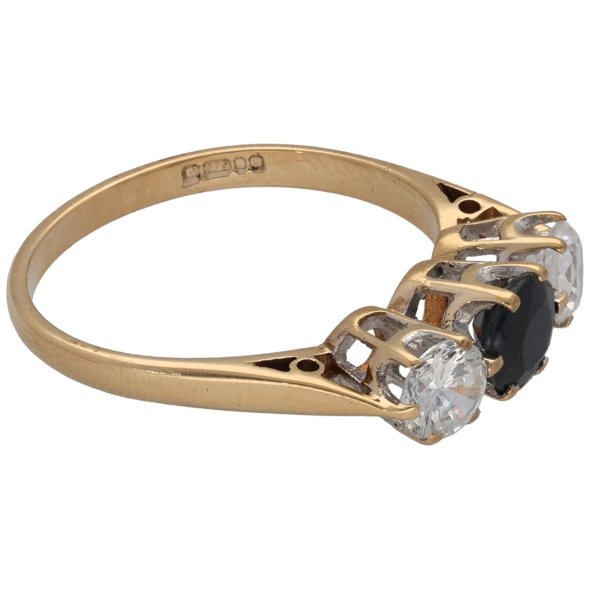 Gold ring with dark center gemstone and two clear round stones, angled side view on prongs