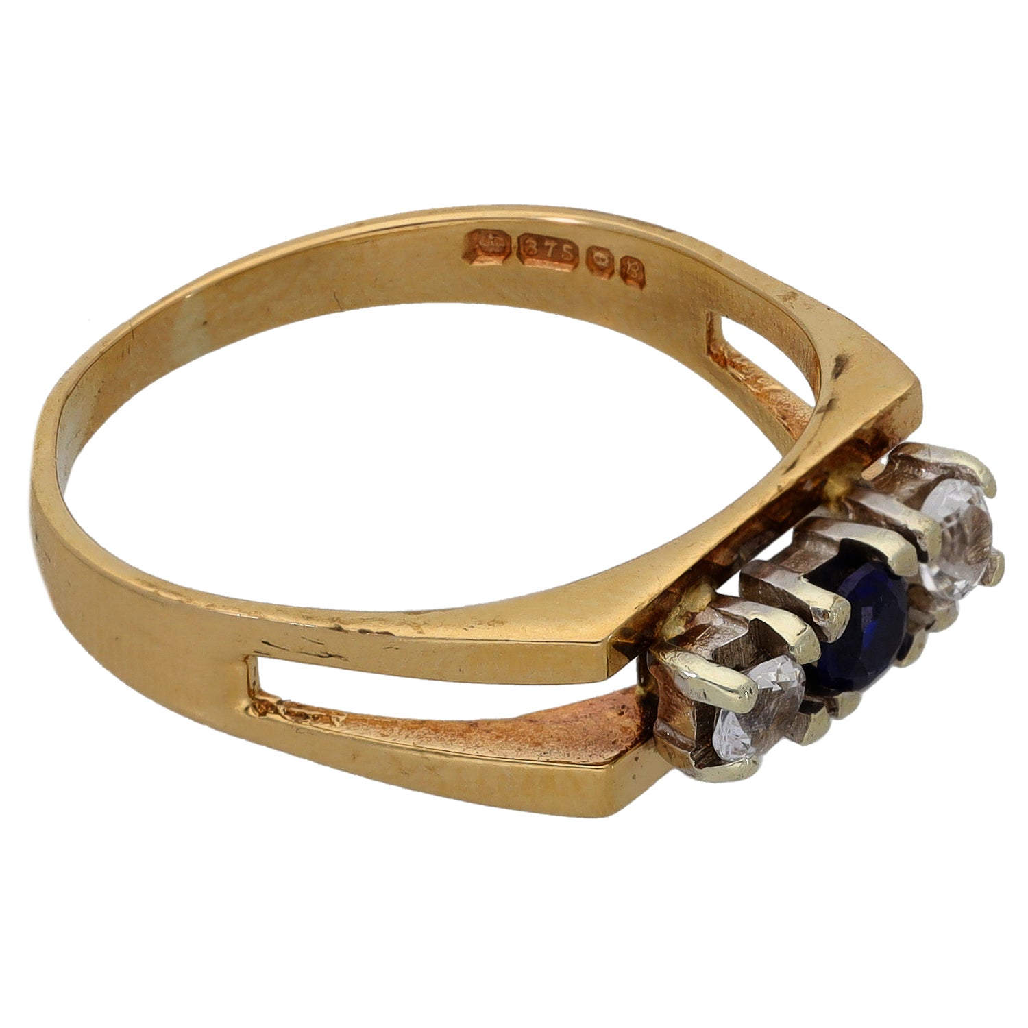 Gold-tone ring band with three-stone setting and dark blue center stone, side view
