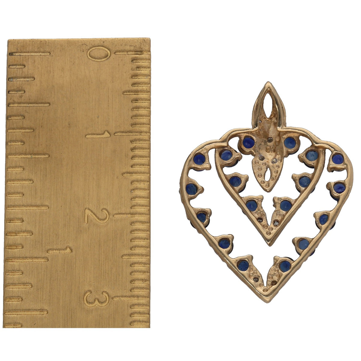 Gold heart pendant with blue sapphire stone border and diamond accents, shown with ruler scale