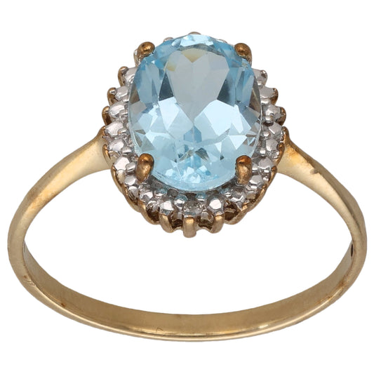 Gold cocktail ring with oval blue topaz center and halo of small diamonds