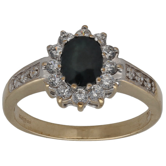 Gold dress ring with oval dark center stone and round clear stones halo