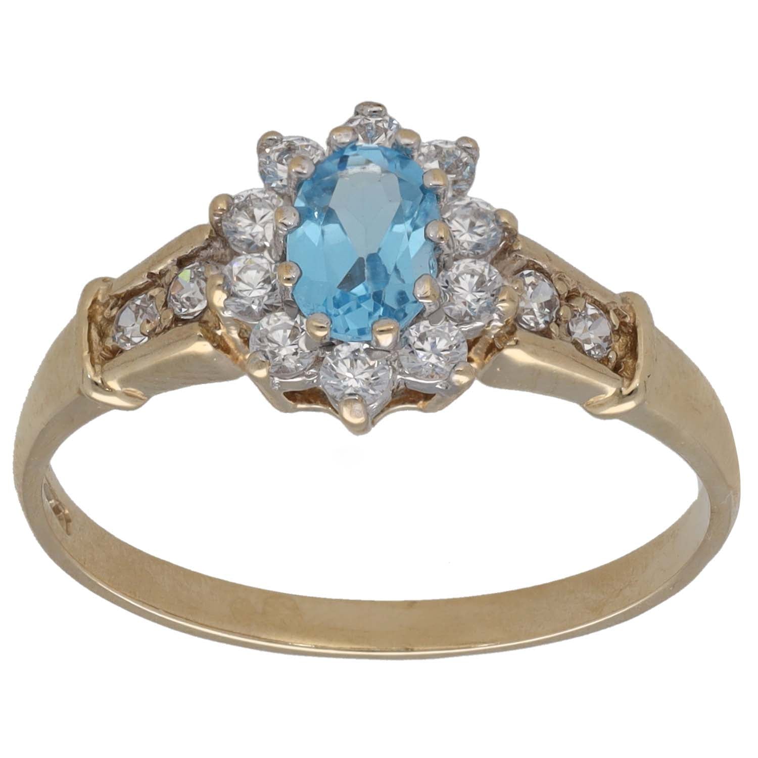 Gold cocktail ring with oval blue gemstone center, surrounded by clear CZ stones