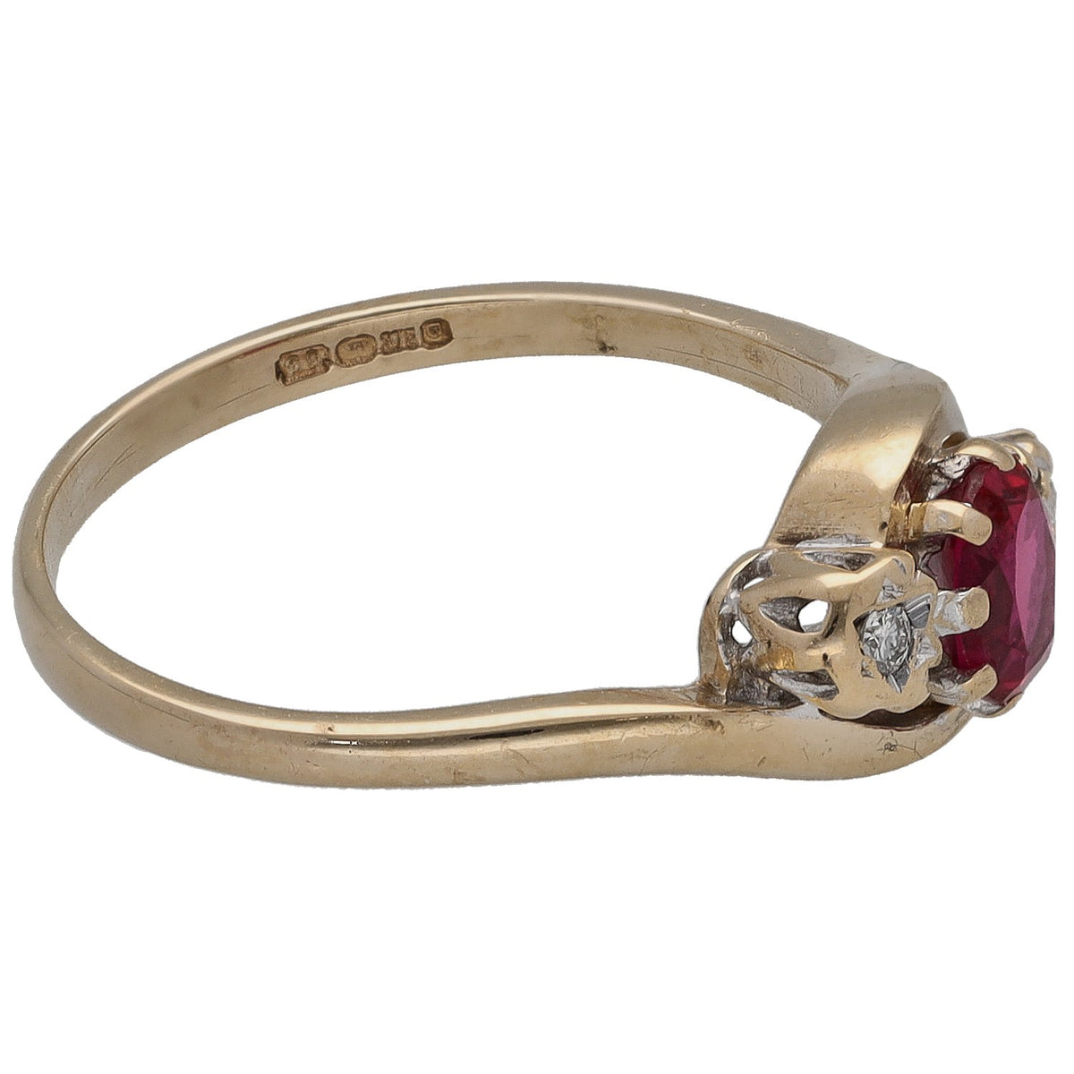 Gold ring profile with round deep red center stone flanked by two small diamonds