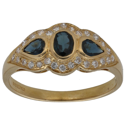Gold cocktail ring with three round dark blue stones and diamond halo details