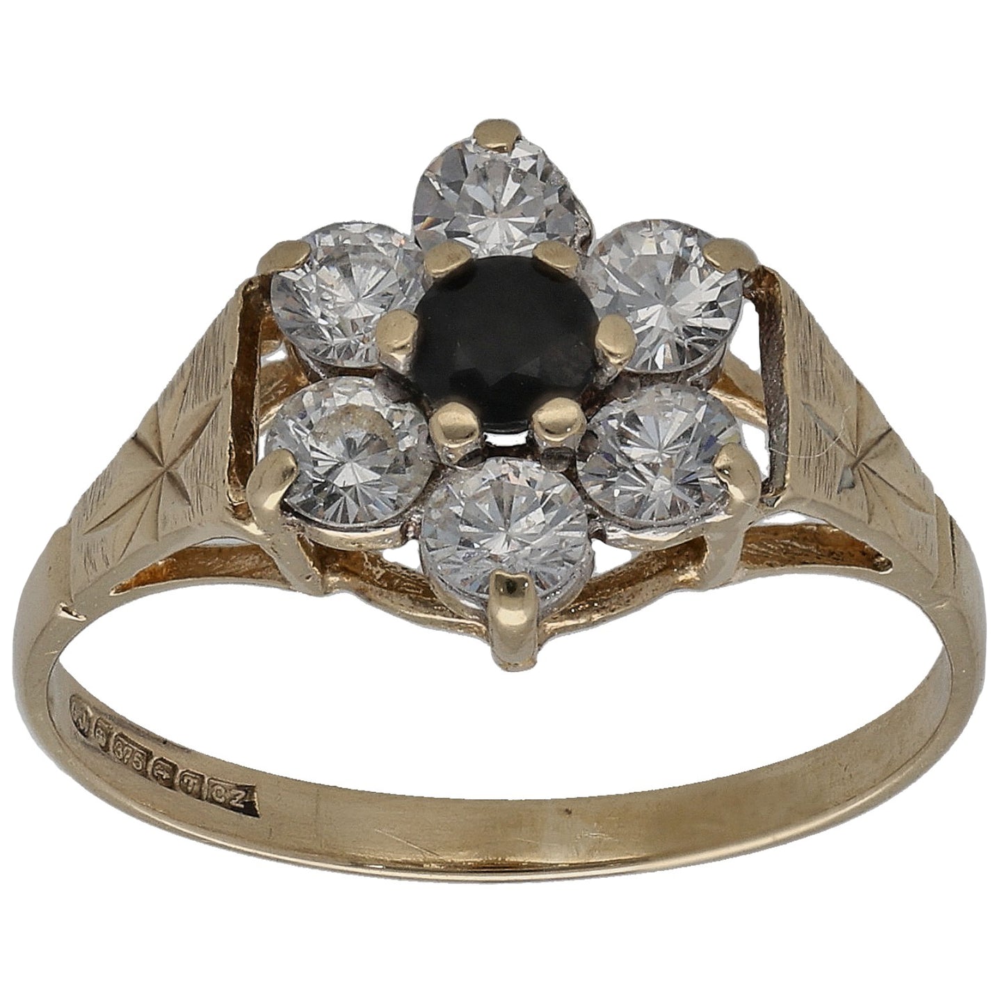 Gold tone ring with six clear stones and a dark center; engraved band, front view.