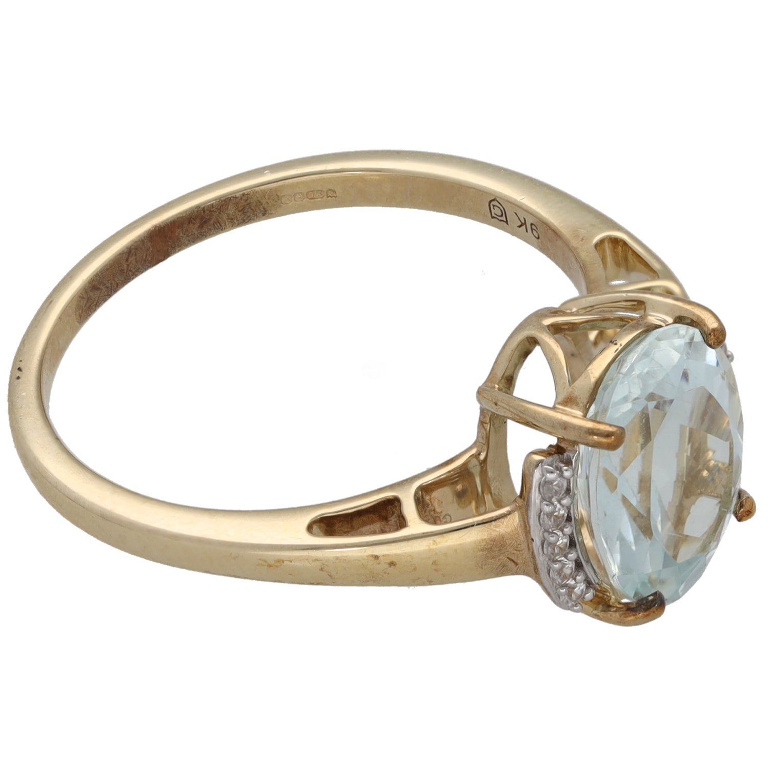 Gold ring side view with oval pale blue center stone and small clear halo stones