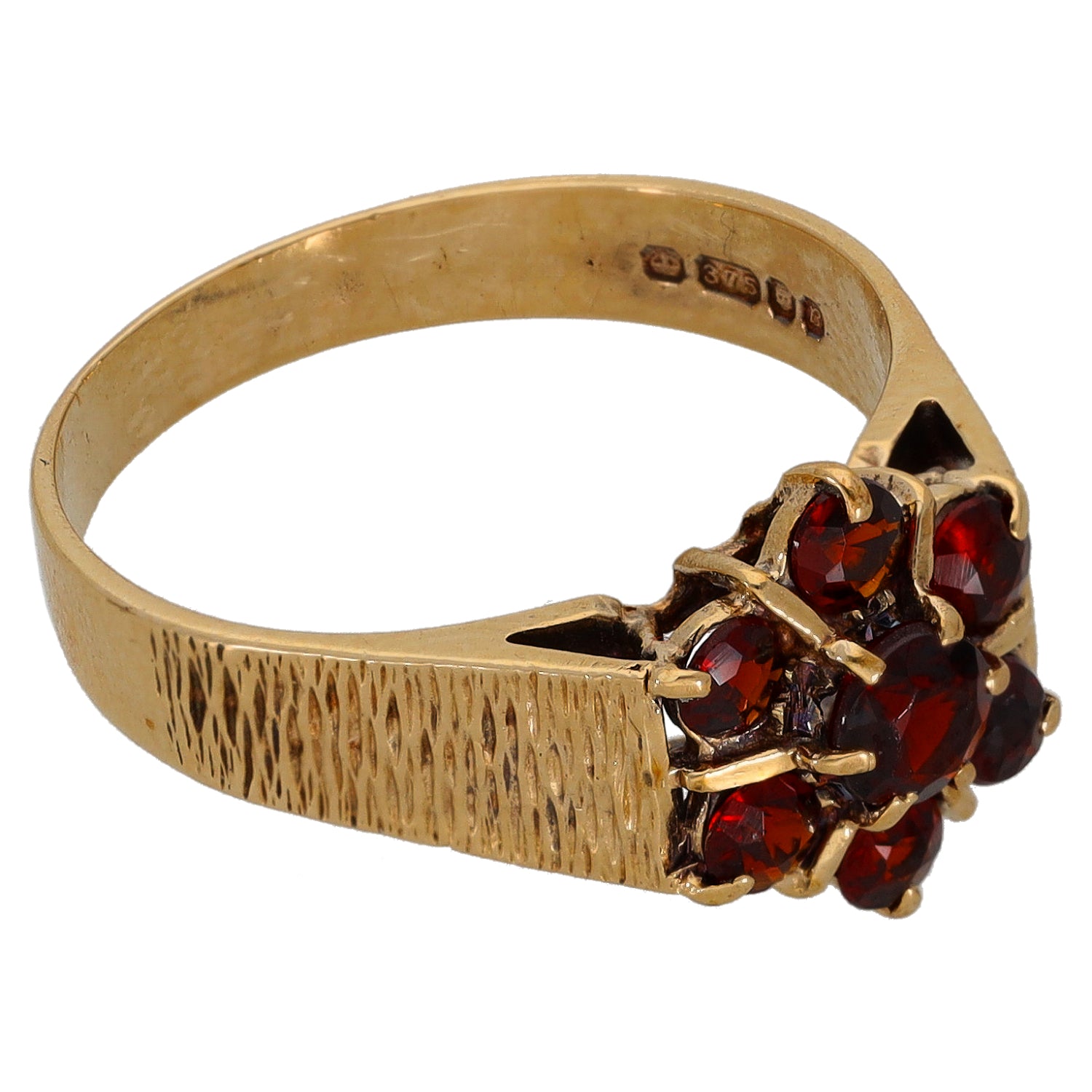 Gold cocktail ring with textured band and oval red gemstone cluster in prong settings