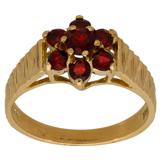 Gold cocktail ring with six red gemstones in flower cluster and ridged band